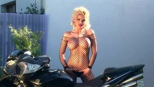 Big-boobed blond taunts on a motorcycle in fishnet