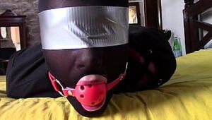 Laura Hardcore is wearing panthyhose and high heels. She's hogtied, masked, eyes covered and ballgagged